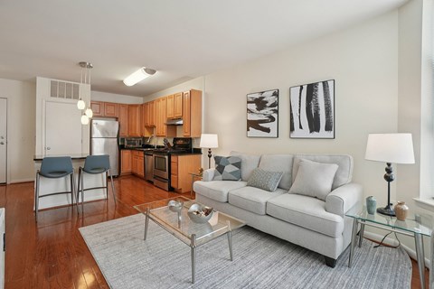 A modern living room with a glass coffee table and a grey sofa.