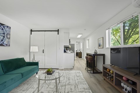A living room with a green couch and a glass coffee table.