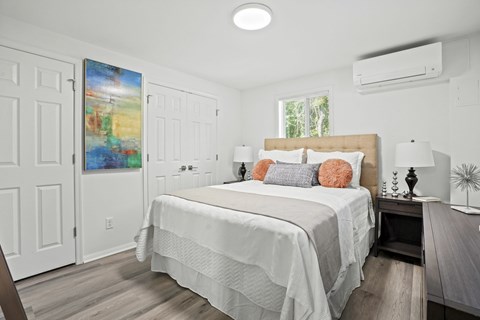 A bedroom with a large bed and a painting on the wall.