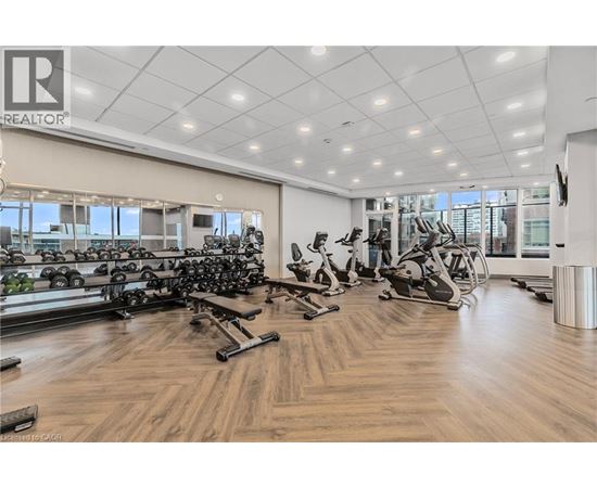 A gym with a variety of exercise equipment including treadmills, stationary bikes, and dumbbells.