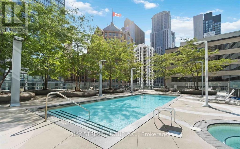 A pool surrounded by trees and a city skyline in the background.