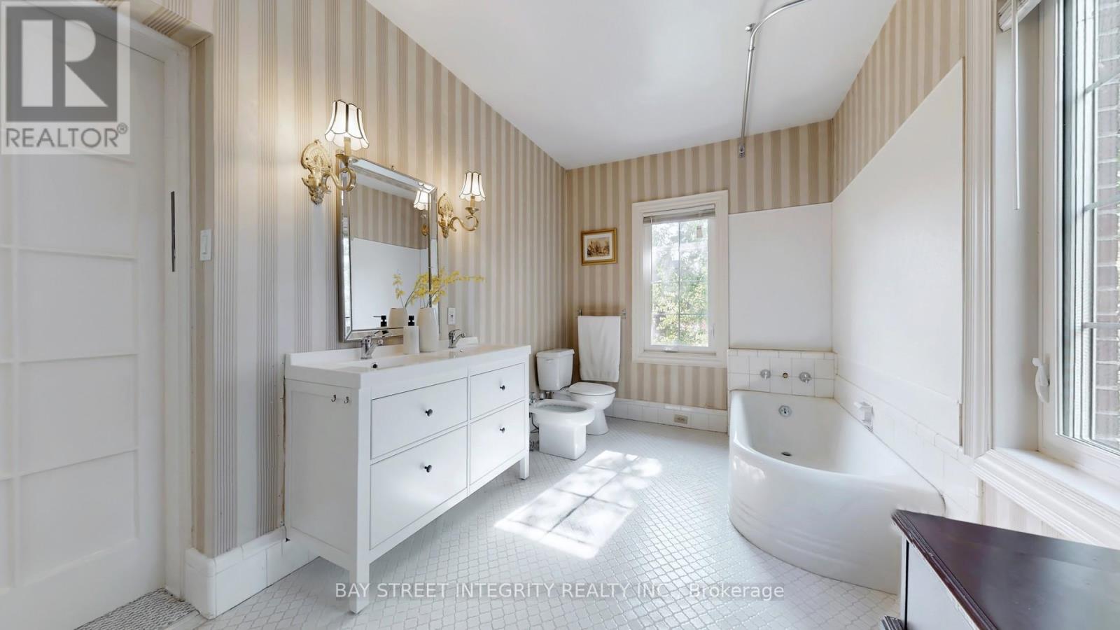A well-lit, spacious bathroom with a white vanity and a bathtub.