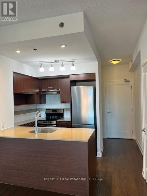 A kitchen with a sink, stove and refrigerator.