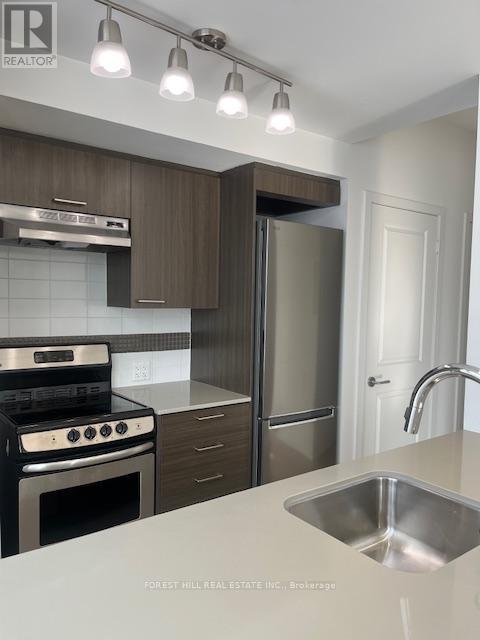 A modern kitchen with a stove top oven, refrigerator, and sink.