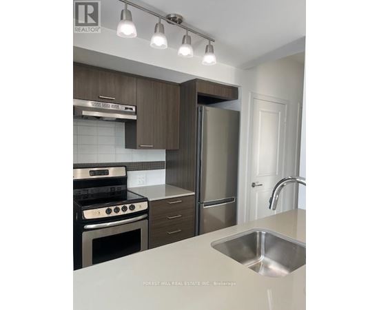 A modern kitchen with a stove top oven, refrigerator, and sink.