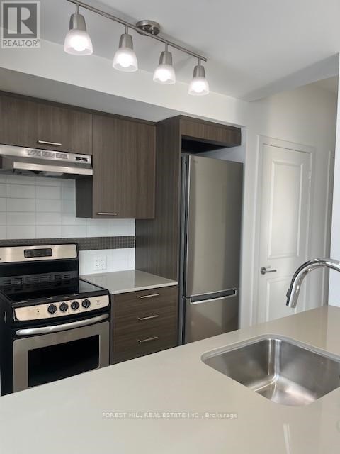 A modern kitchen with a stove top oven, refrigerator, and sink.