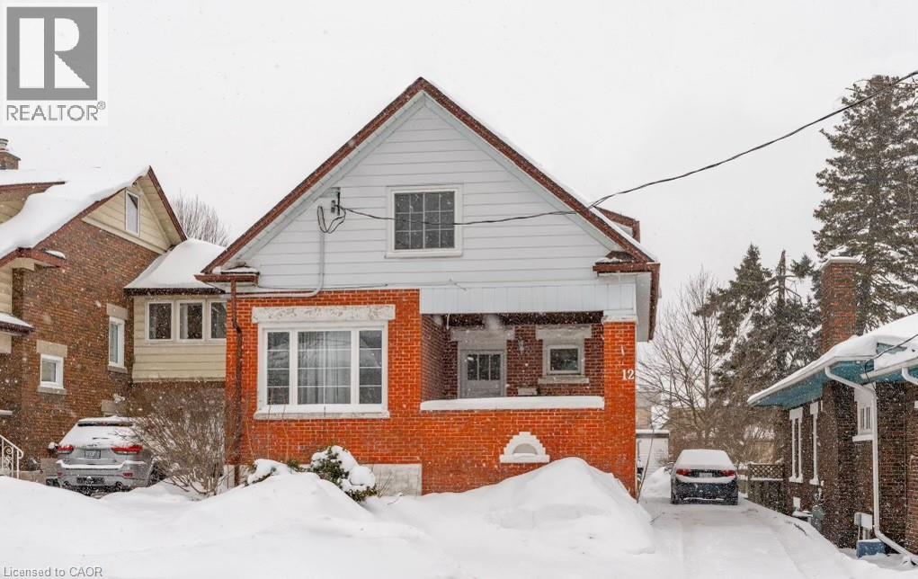 A house with a red brick wall and a white roof is surrounded by snow.