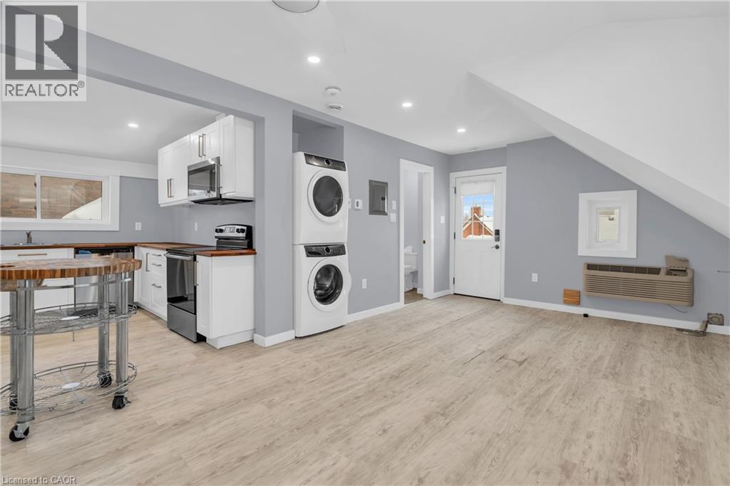A well-lit, spacious laundry room with a washer and dryer, a dining table, and a kitchen area in the background.