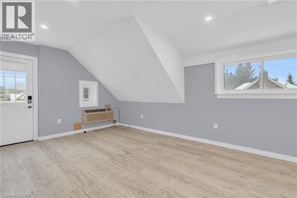 A room with a white door and a window with a view of houses and trees outside.