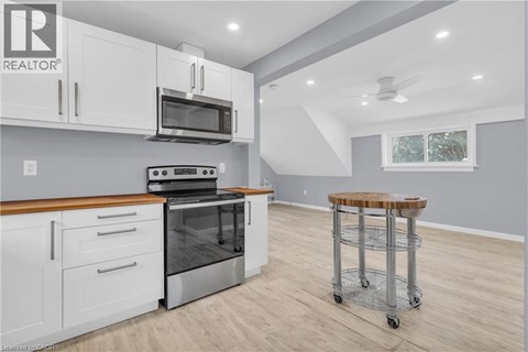 A modern kitchen with white cabinets and a wooden countertop.