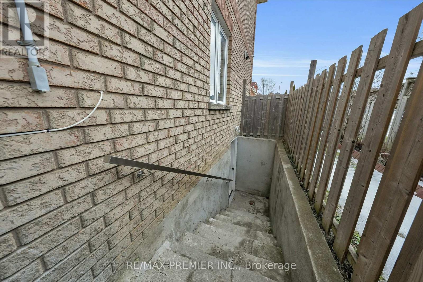 A brick wall with a window and a wooden fence.