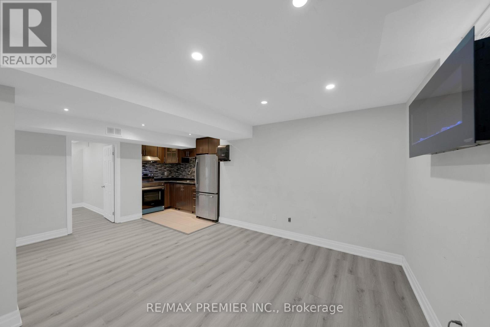 A spacious room with a grey carpet and a flat screen TV mounted on the wall.