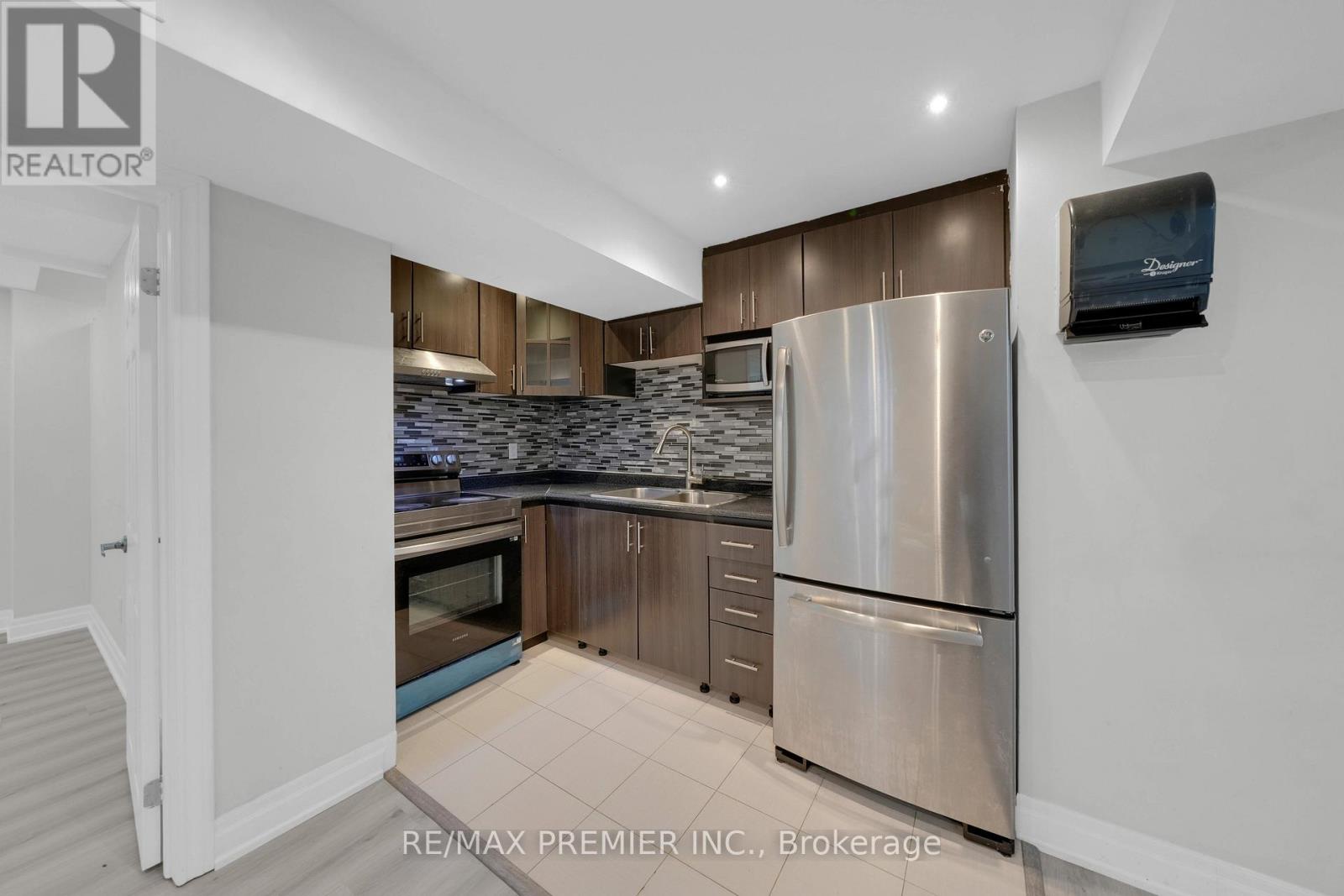 A kitchen with a refrigerator, microwave, and oven.
