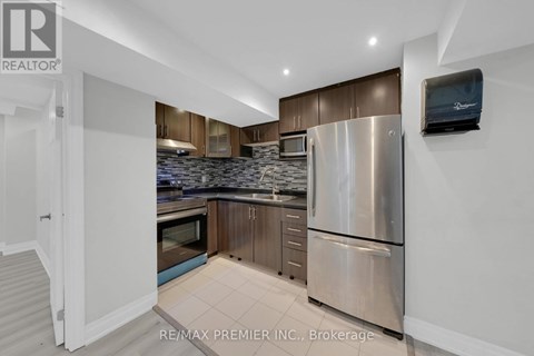 A kitchen with a refrigerator, microwave, and oven.