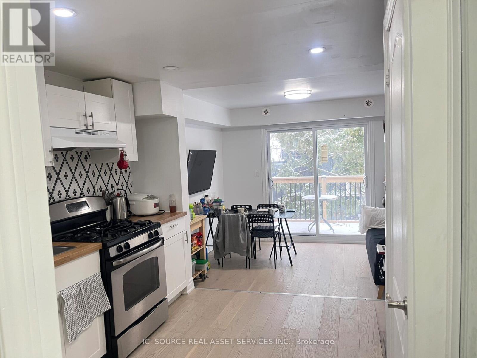 A kitchen with a stove top oven and a dining table with chairs.