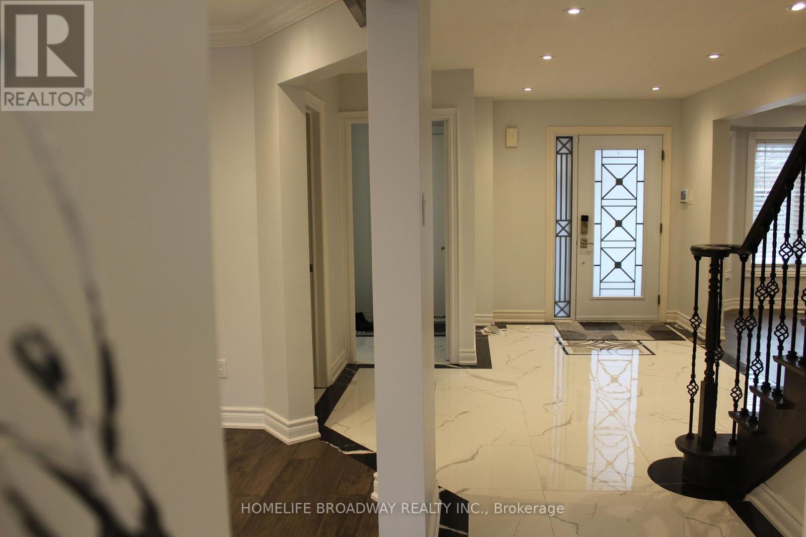 A hallway with a marble floor and a staircase with a black railing.