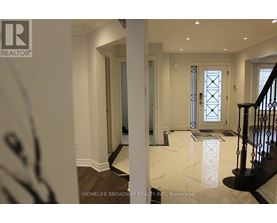 A hallway with a marble floor and a staircase with a black railing.