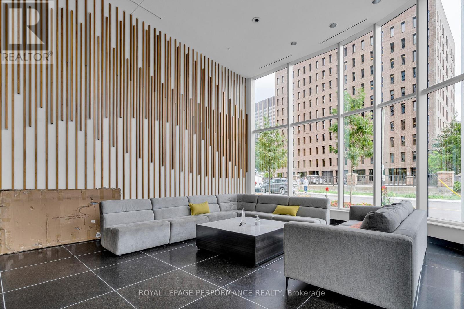A modern living room with a grey sofa and a wooden panelled wall.