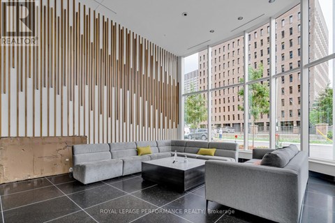 A modern living room with a grey sofa and a wooden panelled wall.