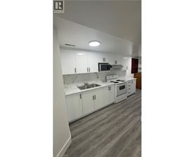 A modern kitchen with white cabinets and a grey floor.