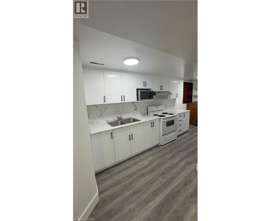 A modern kitchen with white cabinets and a grey floor.