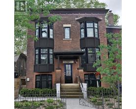 A brown brick house with a black front door and windows.