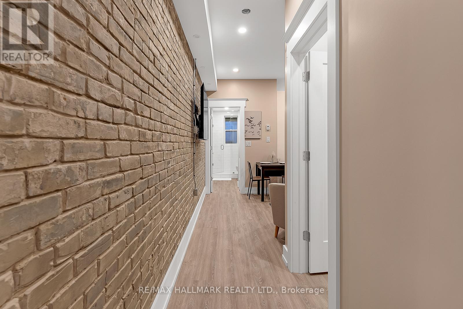 A hallway with a brick wall on the left and a white door on the right.