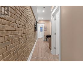 A hallway with a brick wall on the left and a white door on the right.
