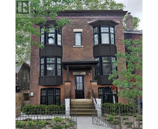 A brown brick house with a black front door and windows.