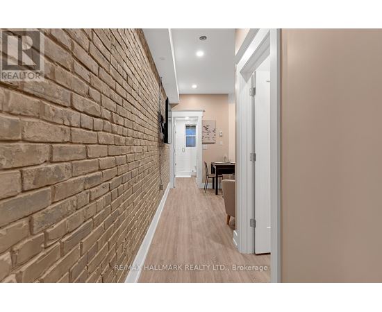 A hallway with a brick wall on the left and a white door on the right.