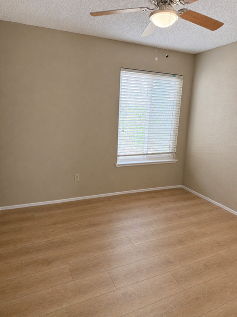 A room with a ceiling fan and a window with blinds.