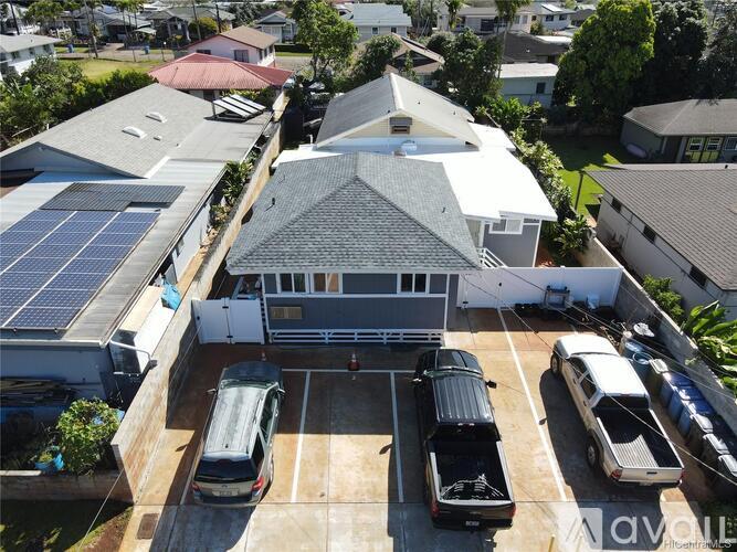 A house with a grey roof and a carport with several cars.