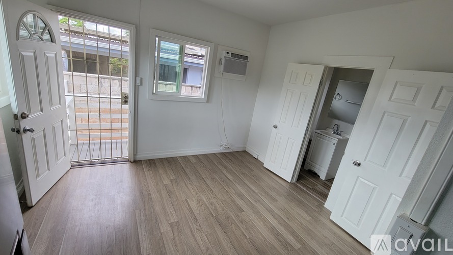 A room with white doors and a window with a view of a balcony.