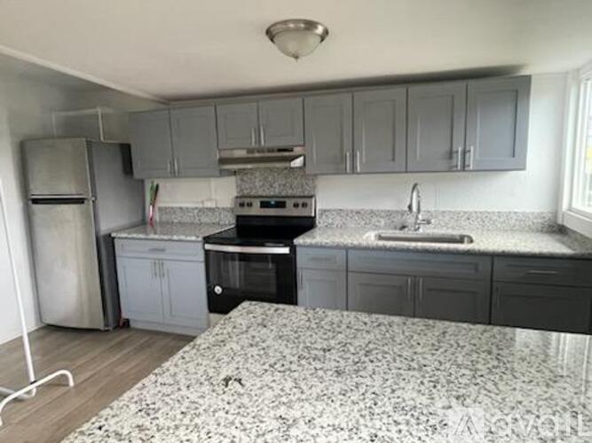 A kitchen with a black stove top oven and a white sink.