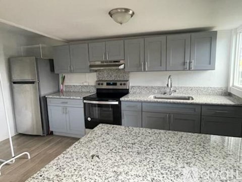 A kitchen with a black stove top oven and a white sink.