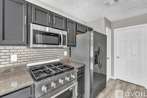 A kitchen with a stove, microwave, and refrigerator.