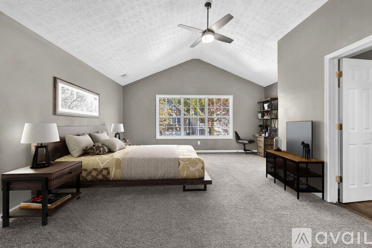 A bedroom with a bed, a desk, a chair, and a ceiling fan.