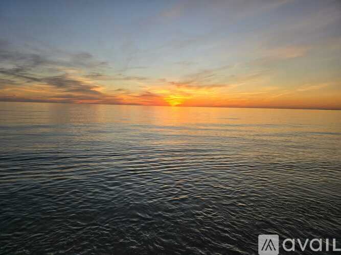 A sunset over the ocean with the sun reflecting on the water.