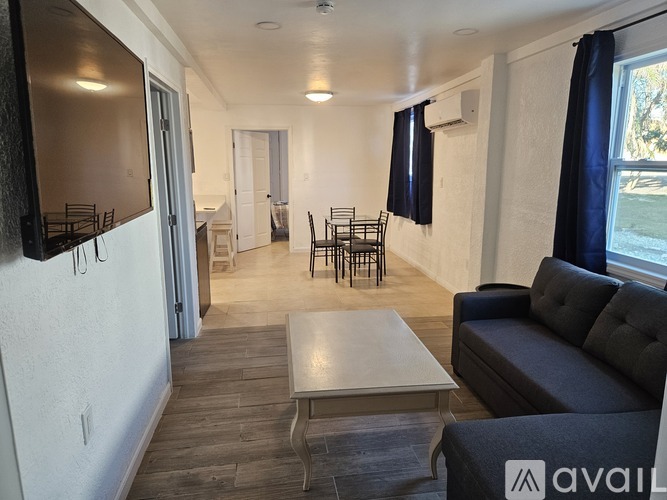 A living room with a grey couch, a white coffee table, and a TV on the wall.