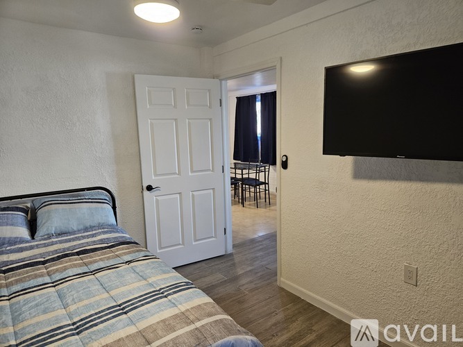 A bedroom with a bed, a door, and a television.