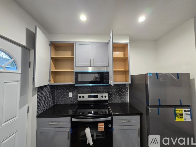 A kitchen with a black countertop and a stainless steel refrigerator.