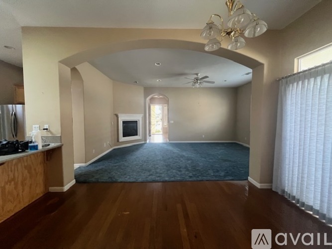 A spacious living room with a dark blue rug and wooden floors.