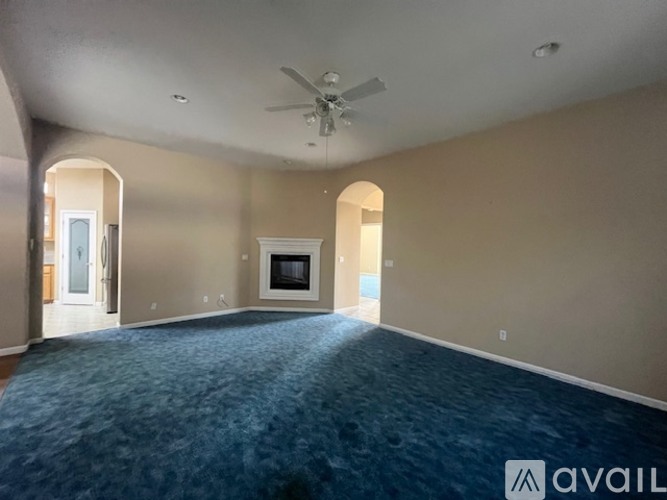A spacious living room with a fireplace and a ceiling fan.