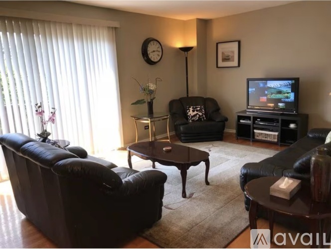 A living room with a black leather couch, a coffee table, and a television.