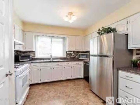 A kitchen with white cabinets and a stainless steel refrigerator.