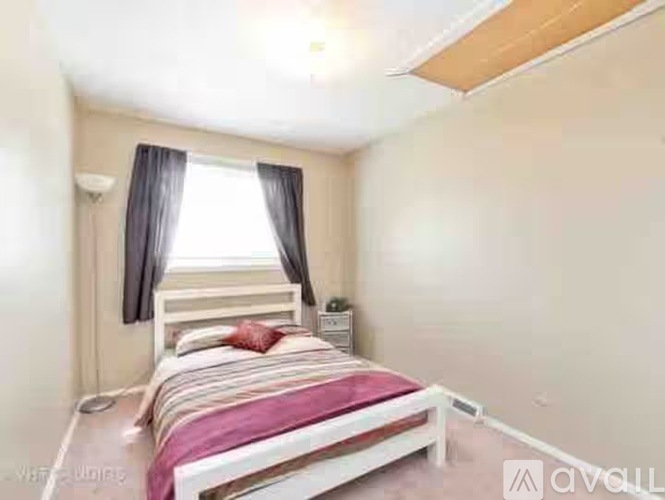 A bedroom with a bed, nightstand, and window with curtains.