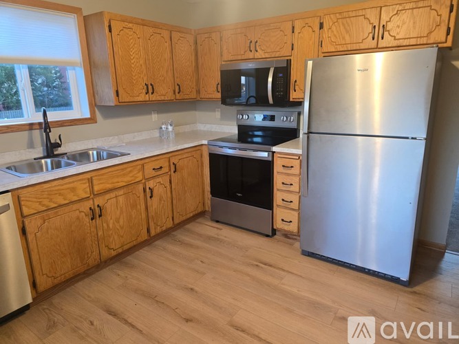 A kitchen with wooden cabinets and a stainless steel refrigerator.