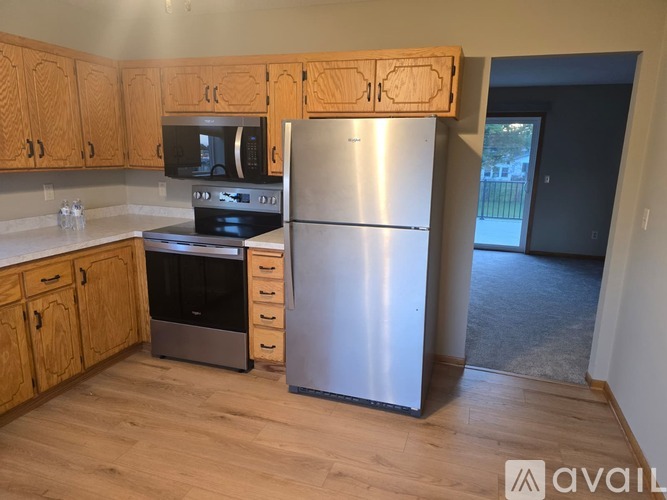 A kitchen with wooden cabinets and a stainless steel refrigerator.