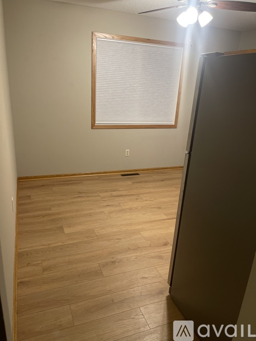 A room with wooden flooring and a window with blinds.