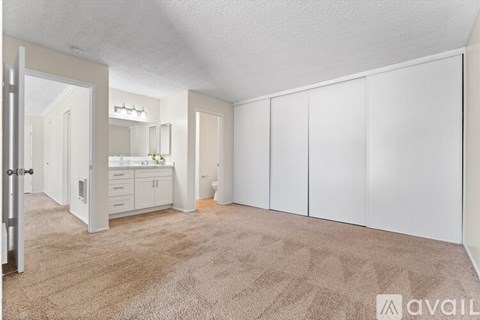A spacious room with white cupboards and a carpeted floor.